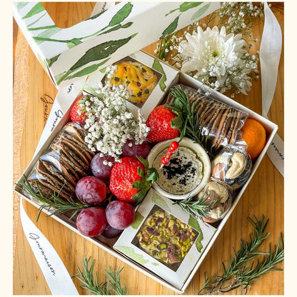 An image of a grazing box that includes cheese, spreads, dry fruits, grapes, and mixed crackers. A gift box with a divine selection of savoury items. 
